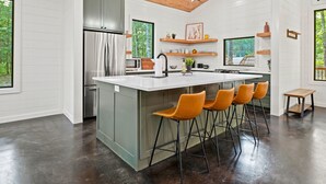 Cozinha moderna com uma ilha grande, banquetas e vista para o exterior.