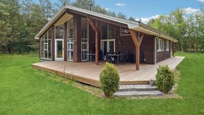 Ein modernes Holzhaus mit einer großen Terrasse, hohen Fenstern und einem überdachten Außenbereich.