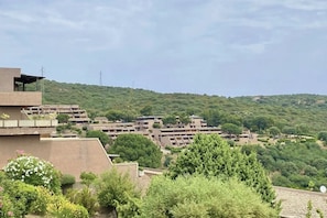 A residential area with multiple apartment buildings, surrounded by greenery and hills.