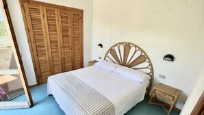 Una camera da letto con un letto grande, un armadio in legno, un comodino e una lampada a parete.