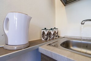 A kitchen with a white kettle, two coffee mugs, and a running faucet. - [Sweet Arona] Beautiful Apartment, Netflix - Wi-Fi (Arona)