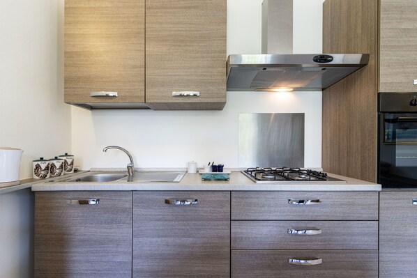 A modern kitchen with wooden cabinets, stainless steel appliances, and a gas stove. - [Sweet Arona] Beautiful Apartment, Netflix - Wi-Fi (Arona)
