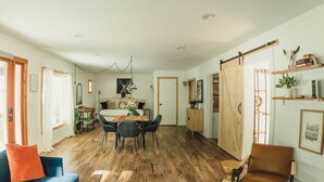A spacious living area with a dining table, sofas, and a sliding barn door. - Modern cottage centrally located with private access to the Rogue River! (Grants Pass)