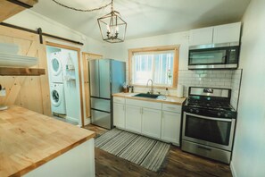 Une cuisine équipée d’un lave-linge, d’un réfrigérateur, d’une cuisinière et d’un four à micro-ondes.