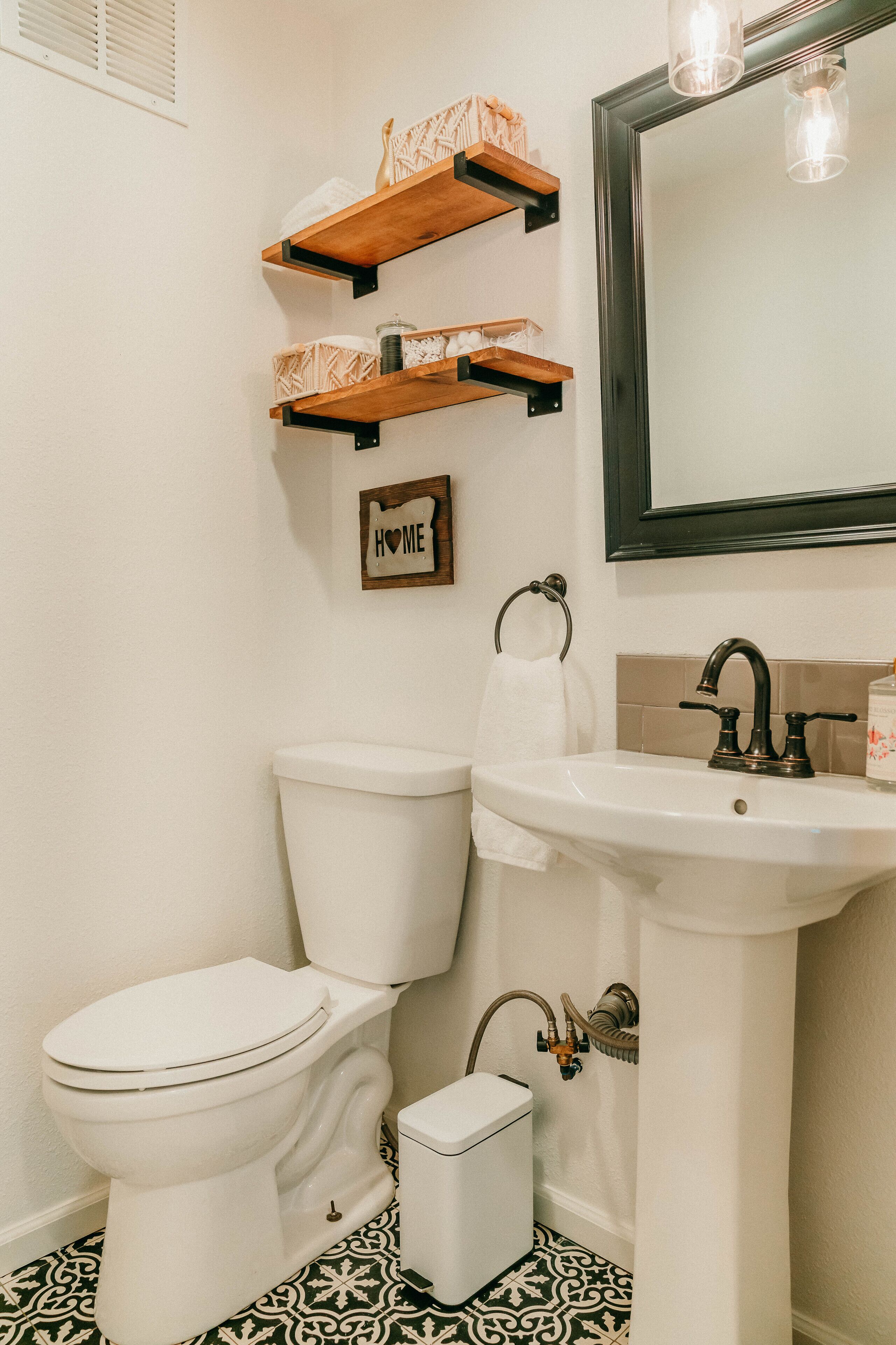 A bathroom with a toilet, sink, and decorative shelves.