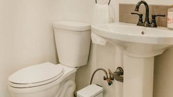A bathroom with a toilet, sink, and decorative shelves.