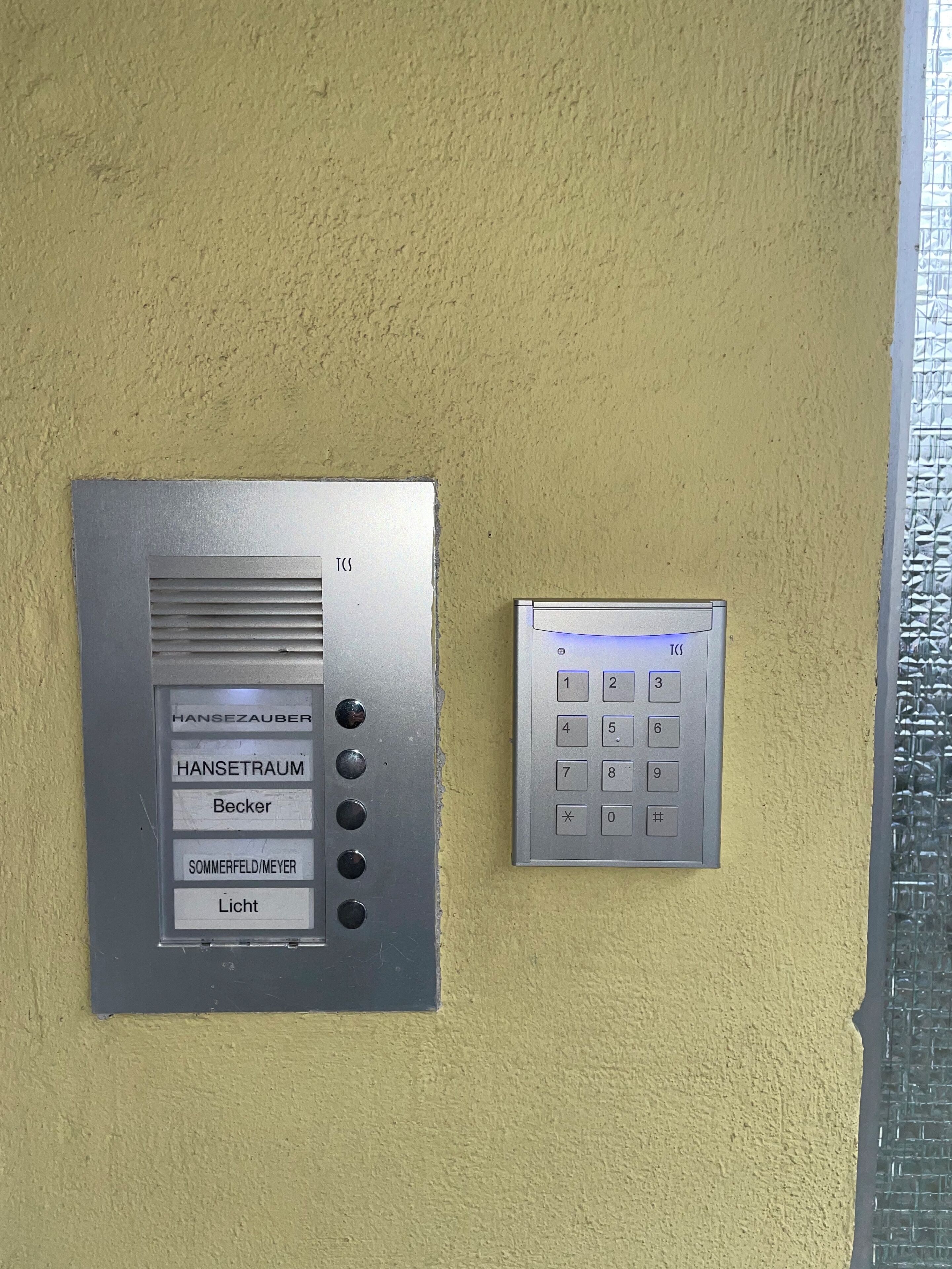 A wall-mounted elevator control panel with buttons labeled 'HANSEZAUBER,' 'HANSETRAUM,' 'Becker,' 'SOMMERFELD/MEYER,' and 'Licht.'