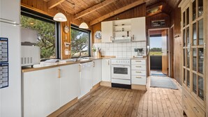 Una cocina moderna con armarios blancos, suelo de madera y vistas al exterior.