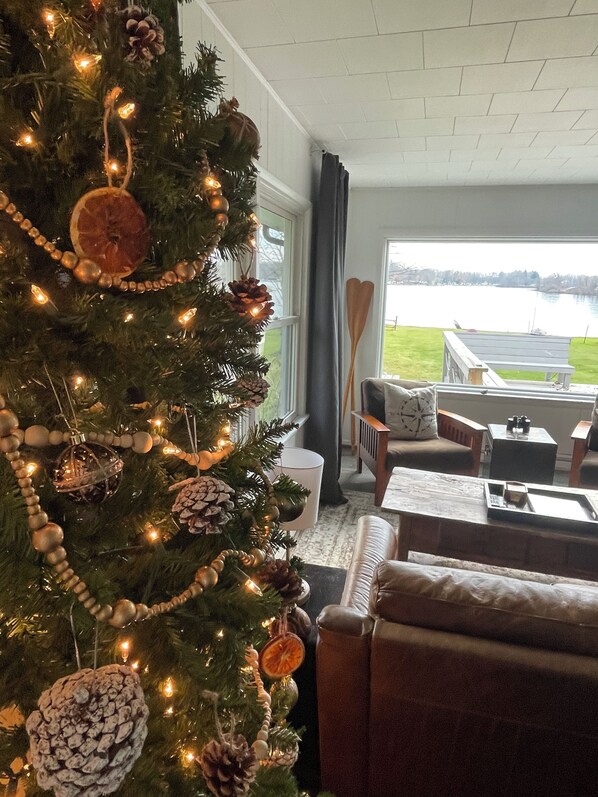 Una sala de estar acogedora con un árbol de Navidad, vista a un lago y una chimenea.