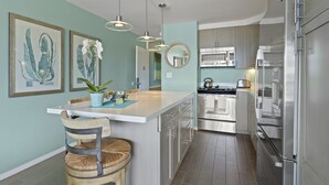 Een moderne keuken met roestvrijstalen apparatuur, een centraal kookeiland met zitplaatsen, en kunstwerken aan de muur.