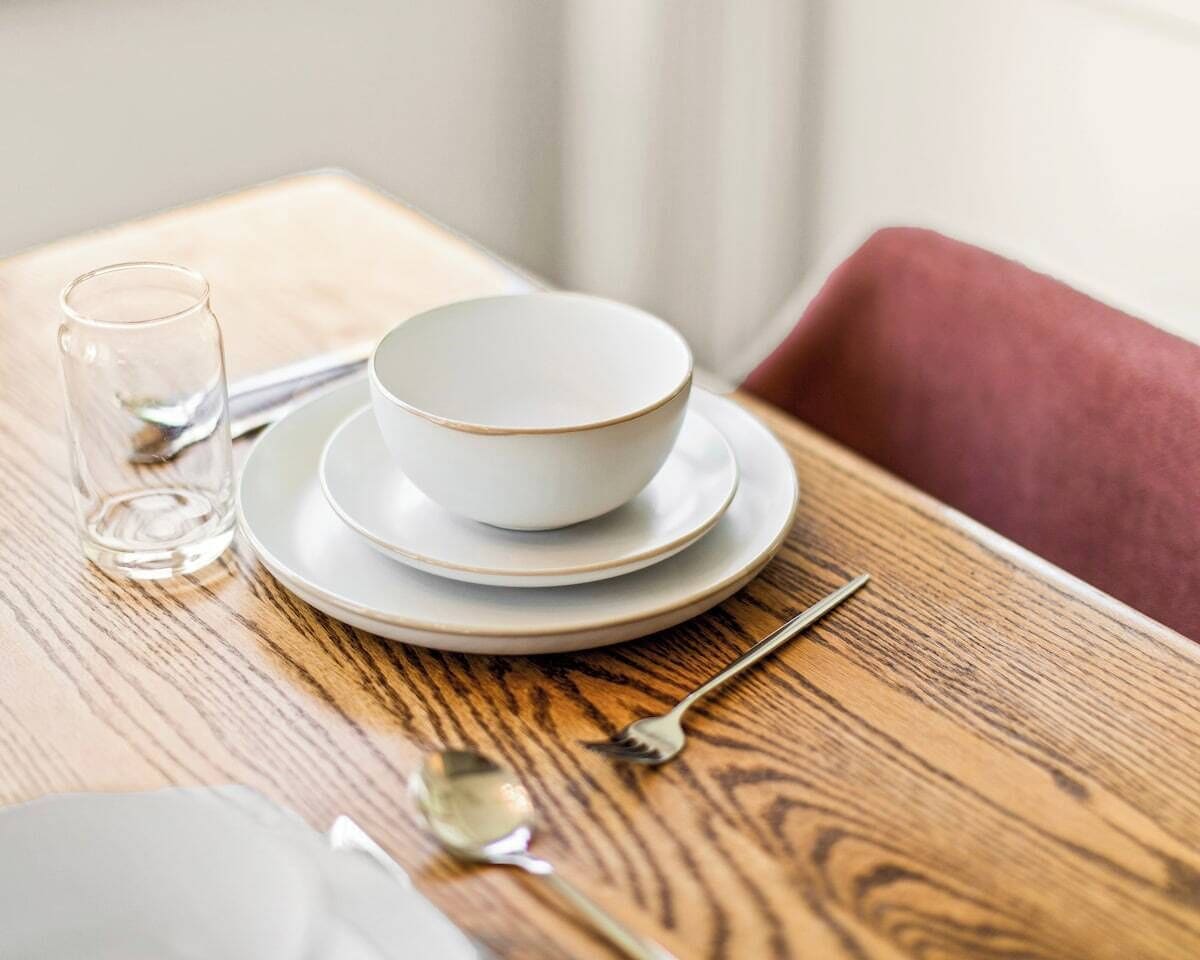 Une table à manger avec un saladier et des assiettes, un verre et des couverts.