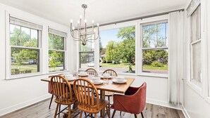 A dining room with a wooden table, four chairs, and a chandelier. - Light and Bright Northland (Superior)