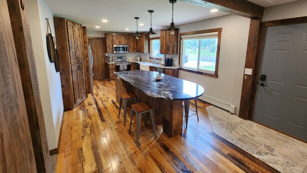 A kitchen with wooden cabinets, a central island, and a large window. - Gorgeous 5 bed Remodel near Downtown Hudson for Groups! (Hudson)