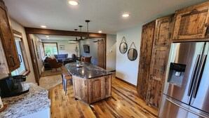 A spacious kitchen with wooden cabinets, a large island, and a stainless steel refrigerator. - Gorgeous 5 bed Remodel near Downtown Hudson for Groups! (Hudson)