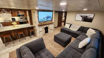 A modern living room with a sectional sofa, ottoman, and a bar area with stools.