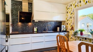 Una cocina moderna con armarios blancos, salpicadero de baldosas negras y ventana con vistas a una casa.