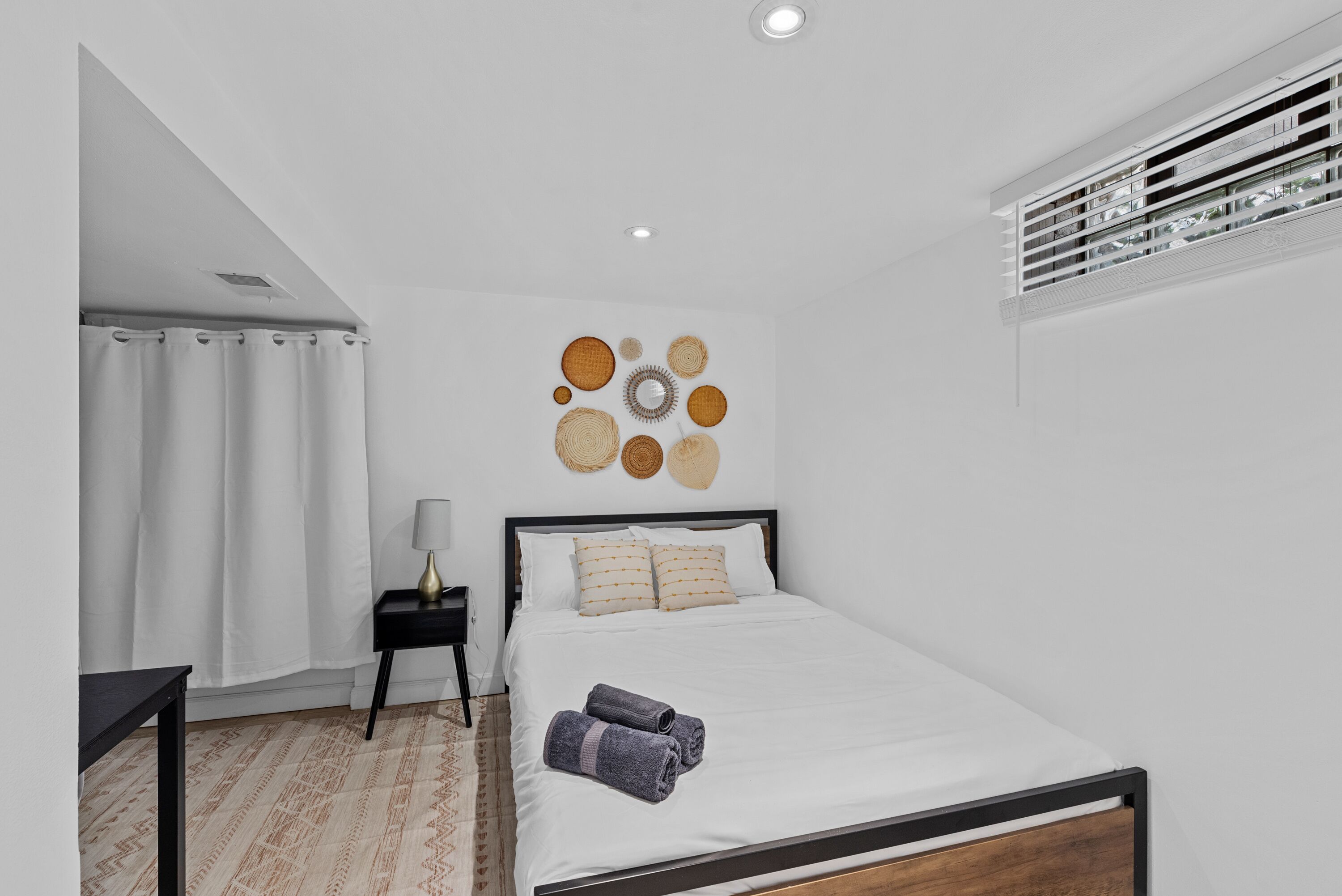 A modern bedroom with a bed, a nightstand, a lamp, and a wall art piece.