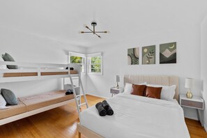 Een slaapkamer met een stapelbed, een klimladder, een groot bed met opgerolde handdoeken, een nachtkastje en wanddecoratie.