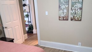 A bedroom with a bed, a patterned rug, and two wall-mounted paintings.