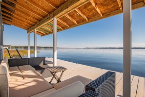Un espacio de estar al aire libre cubierto con vistas a un lago tranquilo y colinas distantes.