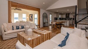 A spacious living area with a sofa, coffee table, and a view of the kitchen and dining area.