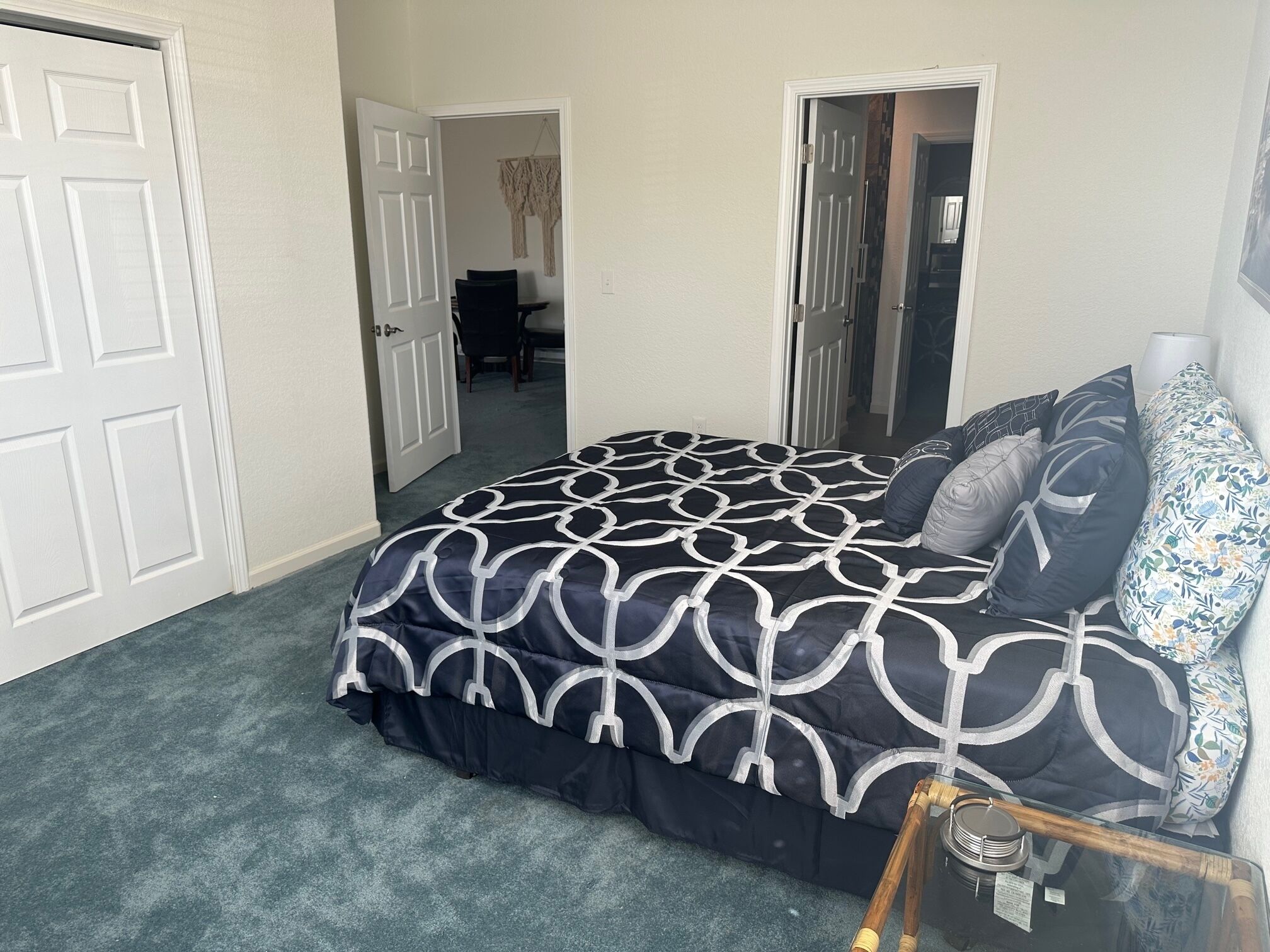 A bedroom with a bed, a bedside table, a mirror, and a door.