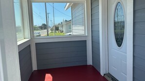 A room with a red floor, a window, and a door with a decorative glass panel. - For your best vacation ever! (Crescent City)