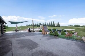 En udendørs patio med grill, træterrasse og et lille skur.