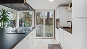 A modern kitchen with a large island, sliding glass doors to a backyard, and a pendant light. - Relaxing sanctuary in desirable area (Hornbæk)