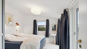 A bedroom with a bed, bedside table, and a window with curtains. - Relaxing sanctuary in desirable area (Hornbæk)