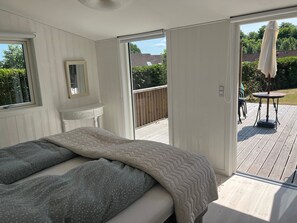 A bedroom with a bed, a window, a door leading to an outdoor deck, and a small table with chairs. - Relaxing sanctuary in desirable area (Hornbæk)