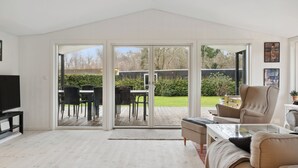A spacious living room with a large sliding glass door leading to an outdoor patio area. - Relaxing sanctuary in desirable area (Hornbæk)