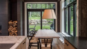 A modern kitchen with a large window, a dining table, and chairs. - Exquisite Rustic Modern Ski Haus Right on MT Abram Bike Park (Greenwood)
