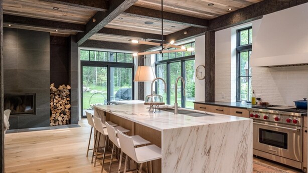 A modern kitchen with a large island, bar stools, a built-in stove, and a fireplace. - Exquisite Rustic Modern Ski Haus Right on MT Abram Bike Park (Greenwood)
