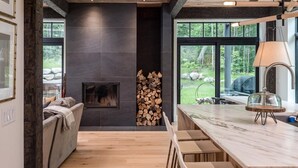 A modern kitchen with a large island, a fireplace, and a view of the outdoors. - Exquisite Rustic Modern Ski Haus Right on MT Abram Bike Park (Greenwood)