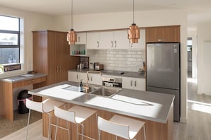 A modern kitchen with a central island, stainless steel appliances, and copper pendant lights.