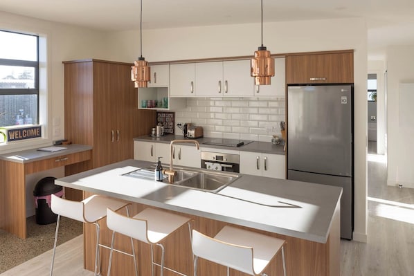 A modern kitchen with a central island, stainless steel appliances, and copper pendant lights.
