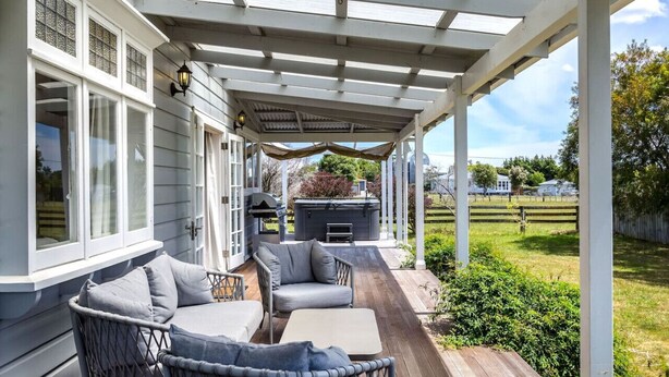 Une terrasse couverte, aménagée avec du mobilier d’extérieur, un barbecue et donnant sur le jardin.