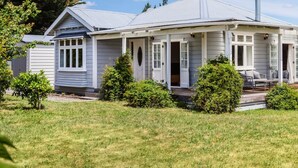 Une maison de plain-pied dotée d’un porche, d’un espace extérieur aménagé et couvert, et d’une pelouse bien entretenue.