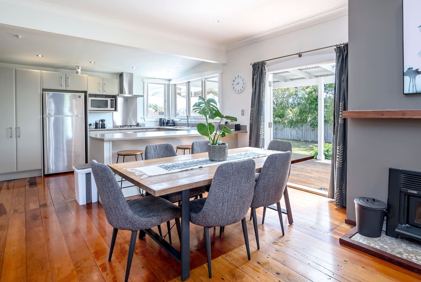 A modern kitchen with a dining area, large windows, and a fireplace.