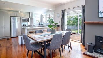 A modern kitchen with a dining area, large windows, and a fireplace.