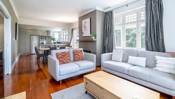 Una sala de estar moderna con un sofá gris, una mesa de centro de madera y un comedor con mesa y sillas.