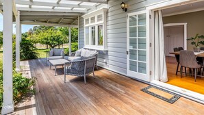 A covered patio with outdoor furniture, a wooden deck, and a view of a garden.