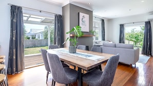 A modern dining area with a wooden table, grey upholstered chairs, and a potted plant.