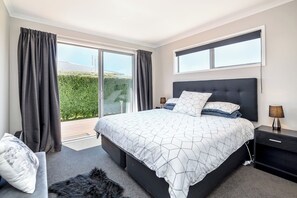 Une chambre avec un grand lit, une table de chevet, une lampe et une vue sur la verdure.