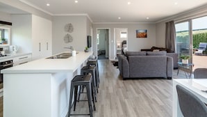 Een moderne keuken met een centraal eiland, een grijze bank en een eethoek met een tafel en stoelen.