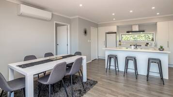 A modern kitchen with a central island, bar stools, and a dining area with a table and chairs.
