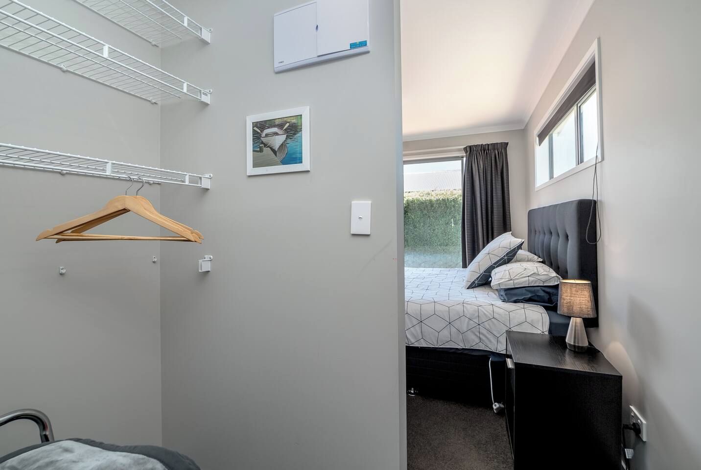 A hotel room with a bed, bedside lamp, and a window with curtains.