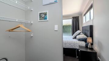 A hotel room with a bed, bedside lamp, and a window with curtains.