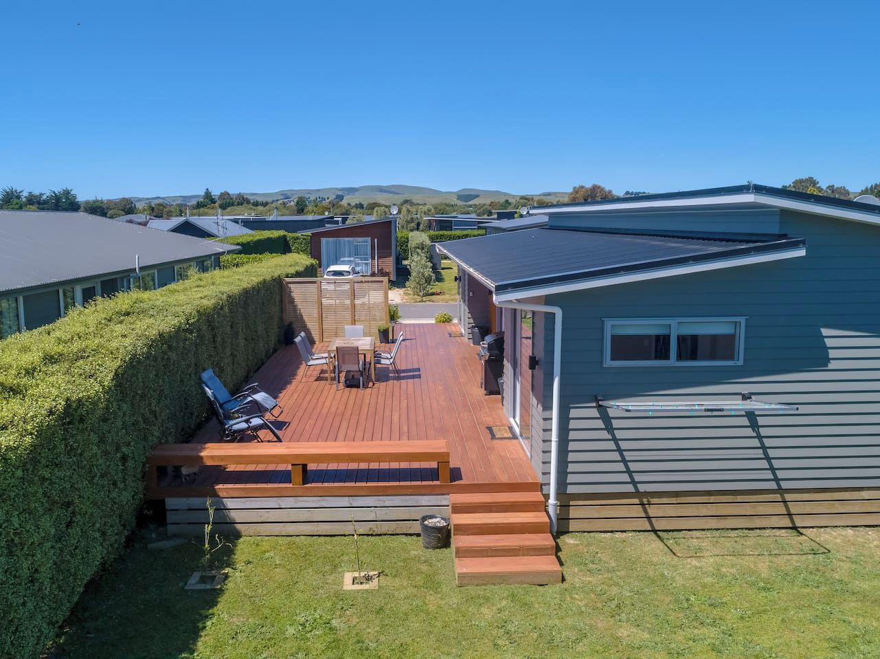 A deck with outdoor furniture, a barbecue area, and a view of the surrounding landscape.